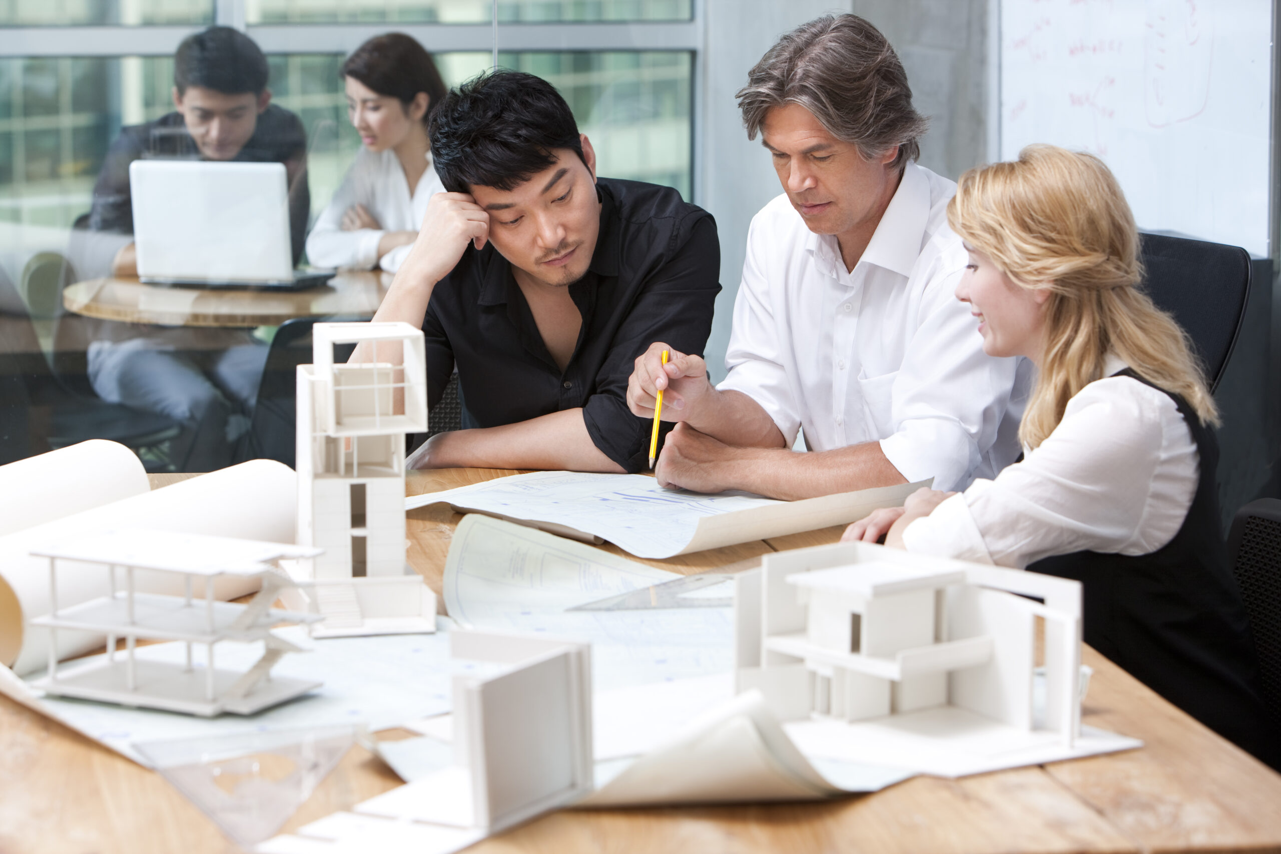 Chinese and western architects studying a blueprint